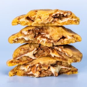 Close-up of stacked homemade cookies with a creamy filling against a blue background.