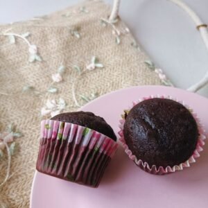 Two chocolate cupcakes with pink wrappers on a pastel pink plate, perfect for dessert.